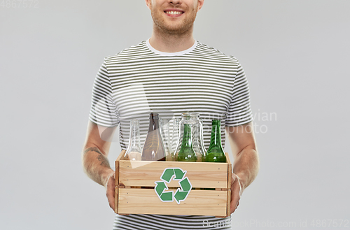 Image of smiling young man sorting glass waste