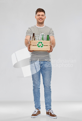 Image of smiling young man sorting glass waste