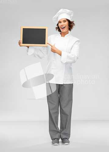 Image of smiling female chef holding black chalkboard