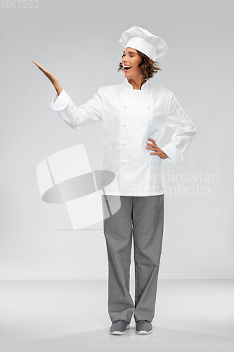 Image of smiling female chef holding something on hand