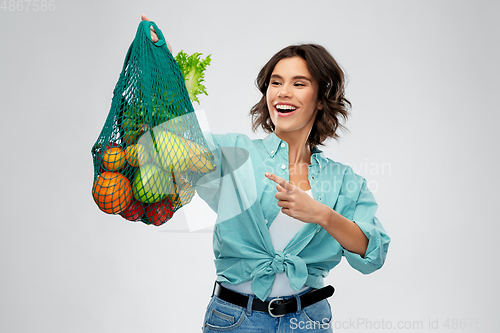 Image of happy smiling woman with food in reusable net bag