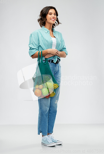 Image of happy smiling woman with food in reusable net bag