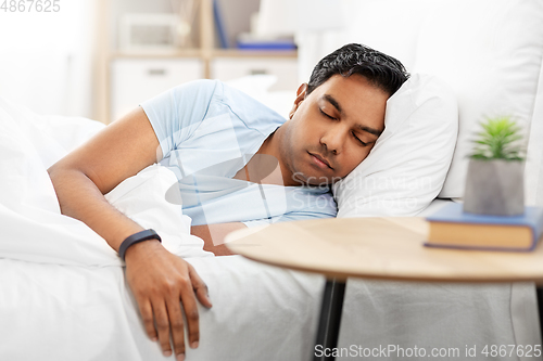 Image of indian man with tracker sleeping in bed at home