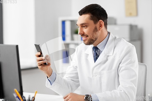 Image of smiling male doctor with smartphone at hospital