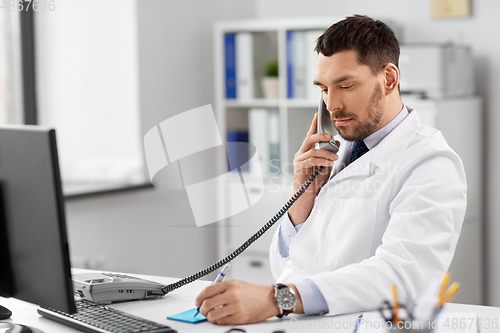 Image of male doctor calling on desk phone at hospital