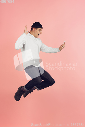 Image of Caucasian young man\'s modern portrait on pink studio background in high jump