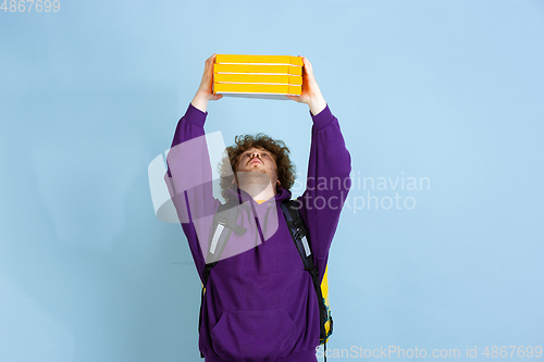 Image of Contacless delivery service during quarantine. Man delivers food and shopping bags during insulation. Emotions of deliveryman isolated on blue background.