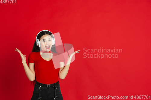 Image of Caucasian young woman\'s monochrome portrait on red studio background, emotional and expressive