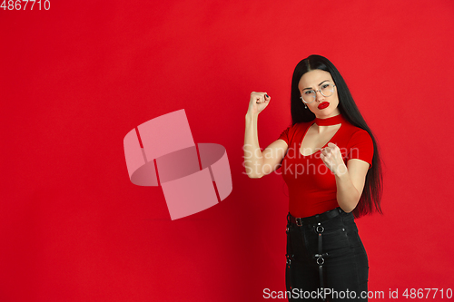 Image of Caucasian young woman\'s monochrome portrait on red studio background, emotional and expressive