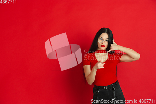 Image of Caucasian young woman\'s monochrome portrait on red studio background, emotional and expressive