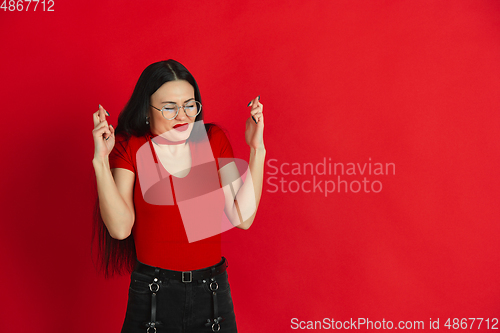 Image of Caucasian young woman\'s monochrome portrait on red studio background, emotional and expressive