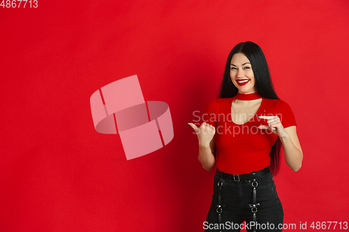 Image of Caucasian young woman\'s monochrome portrait on red studio background, emotional and expressive