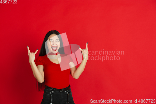 Image of Caucasian young woman\'s monochrome portrait on red studio background, emotional and expressive