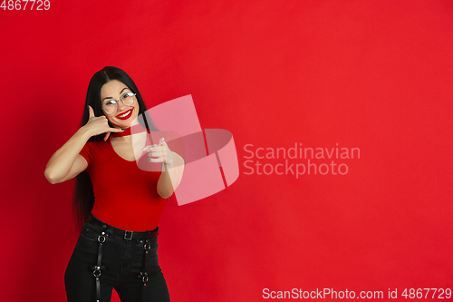 Image of Caucasian young woman\'s monochrome portrait on red studio background, emotional and expressive