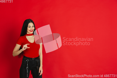 Image of Caucasian young woman\'s monochrome portrait on red studio background, emotional and expressive