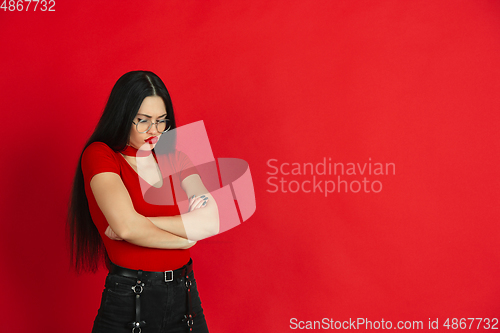 Image of Caucasian young woman\'s monochrome portrait on red studio background, emotional and expressive