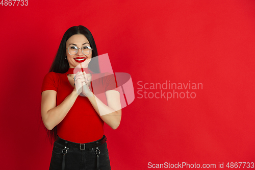 Image of Caucasian young woman\'s monochrome portrait on red studio background, emotional and expressive