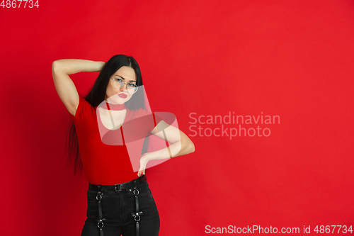 Image of Caucasian young woman\'s monochrome portrait on red studio background, emotional and expressive