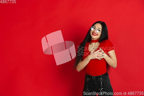 Image of Caucasian young woman\'s monochrome portrait on red studio background, emotional and expressive