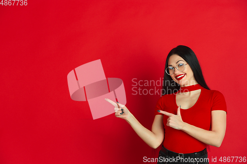 Image of Caucasian young woman\'s monochrome portrait on red studio background, emotional and expressive