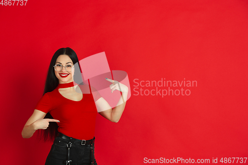 Image of Caucasian young woman\'s monochrome portrait on red studio background, emotional and expressive