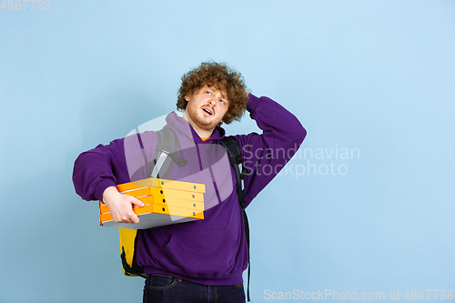 Image of Contacless delivery service during quarantine. Man delivers food and shopping bags during insulation. Emotions of deliveryman isolated on blue background.