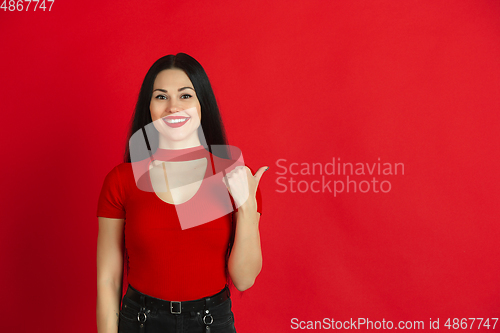 Image of Caucasian young woman\'s monochrome portrait on red studio background, emotional and expressive