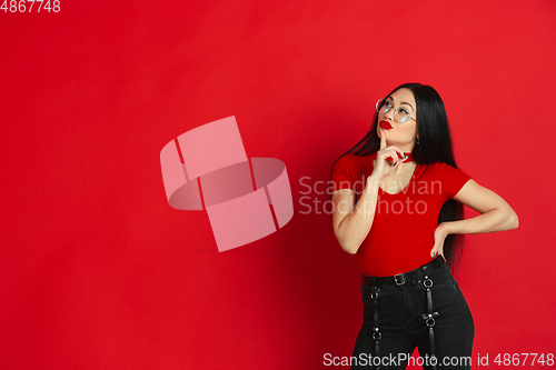 Image of Caucasian young woman\'s monochrome portrait on red studio background, emotional and expressive