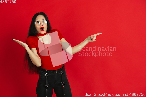 Image of Caucasian young woman\'s monochrome portrait on red studio background, emotional and expressive