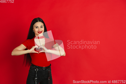 Image of Caucasian young woman\'s monochrome portrait on red studio background, emotional and expressive