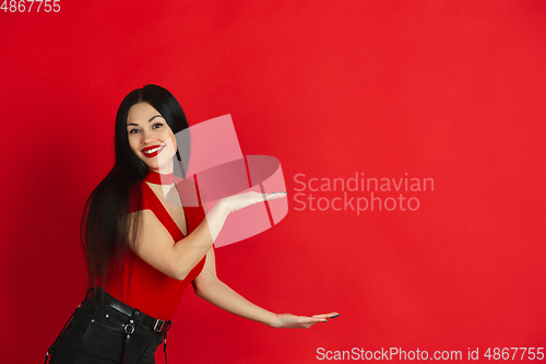 Image of Caucasian young woman\'s monochrome portrait on red studio background, emotional and expressive