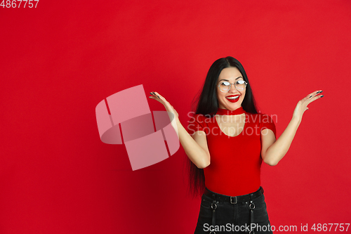 Image of Caucasian young woman\'s monochrome portrait on red studio background, emotional and expressive