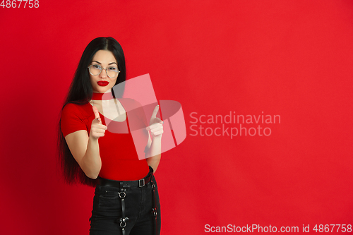Image of Caucasian young woman\'s monochrome portrait on red studio background, emotional and expressive