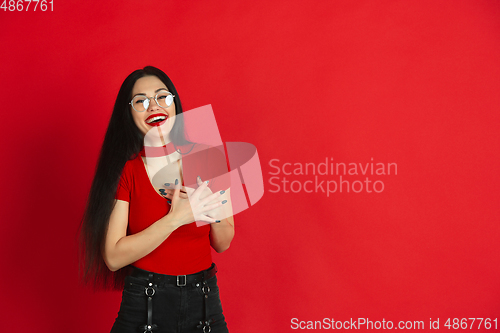 Image of Caucasian young woman\'s monochrome portrait on red studio background, emotional and expressive