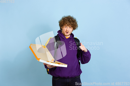 Image of Contacless delivery service during quarantine. Man delivers food and shopping bags during insulation. Emotions of deliveryman isolated on blue background.