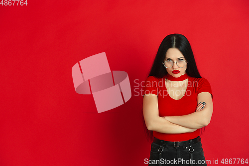 Image of Caucasian young woman\'s monochrome portrait on red studio background, emotional and expressive
