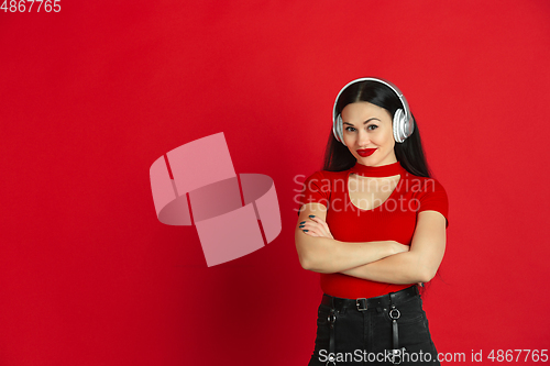 Image of Caucasian young woman\'s monochrome portrait on red studio background, emotional and expressive