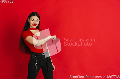 Image of Caucasian young woman\'s monochrome portrait on red studio background, emotional and expressive