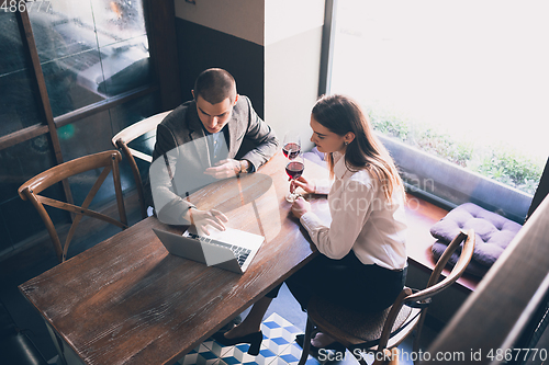 Image of Cheerful man and woman talking, enjoying a wine at the wine shop, cafe