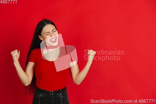Image of Caucasian young woman\'s monochrome portrait on red studio background, emotional and expressive