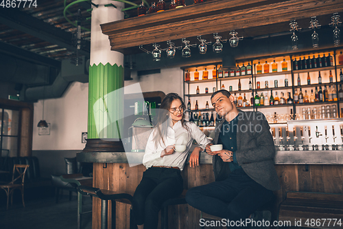 Image of Cheerful man and woman talking, enjoying a coffee at the coffee shop, cafe, bar