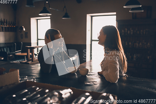 Image of Cheerful man and woman talking, enjoying a coffee at the coffee shop, cafe, bar