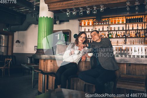 Image of Cheerful man and woman talking, enjoying a coffee at the coffee shop, cafe, bar