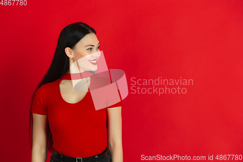 Image of Caucasian young woman\'s monochrome portrait on red studio background, emotional and expressive