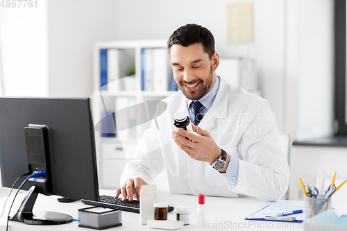 Image of male doctor with medicine and computer at hospital
