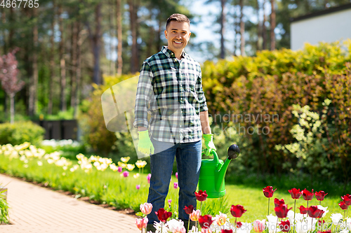 Image of happy man with watering can and flowers at garden