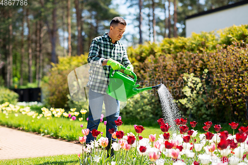 Image of middle-aged man watering flowers at garden