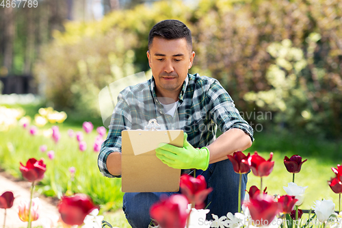 Image of man with clipboard and flowers at summer garden