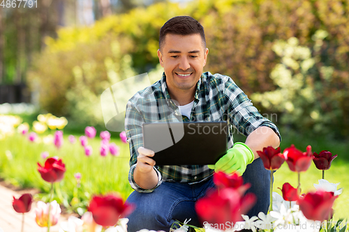 Image of man with tablet pc and flowers at summer garden