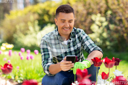 Image of middle-aged man with smartphone at flower garden